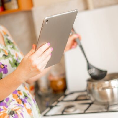 Woman cooking while looking at her iPad.