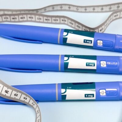 Ozempic pen and measuring tape on a blue background.