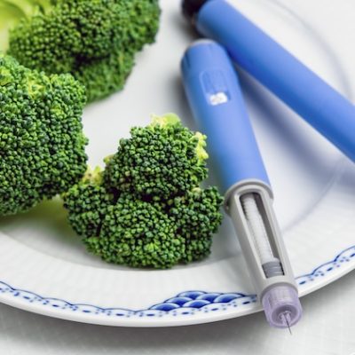 Ozempic insulin pen and broccoli on a plate.