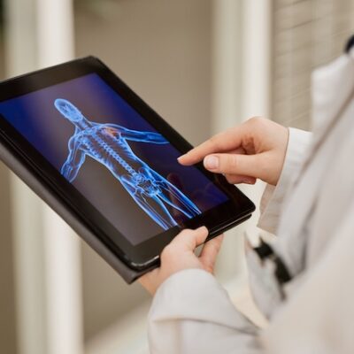 Doctor looking at tablet computer with an image of a body scan on it.