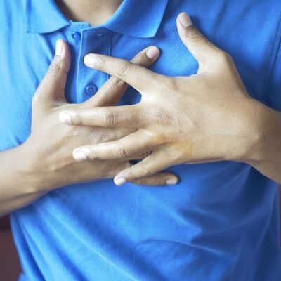 Young man suffering pain in heart and holding chest with hands.