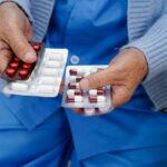 Elderly woman holding a range of medications in her hands.