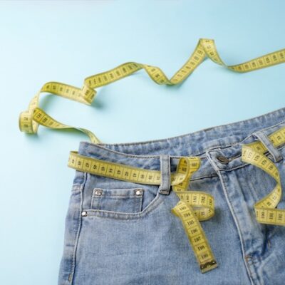 Jeans and measuring tape on a blue background.