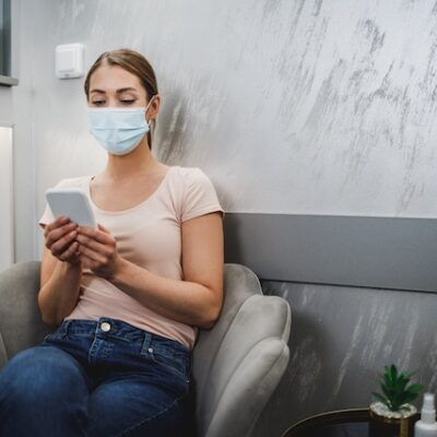 A young woman wearing face mask and using her smartphone.