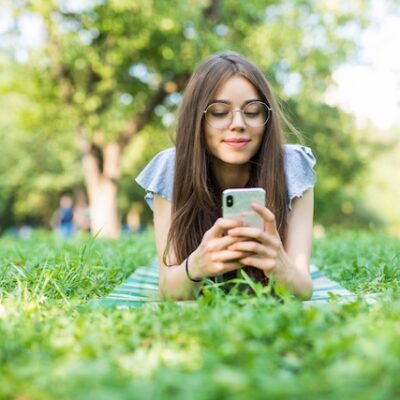 Young woman lying on the grass using her mobile phone.