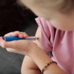 Young girl using an Ozempic pen on herself.