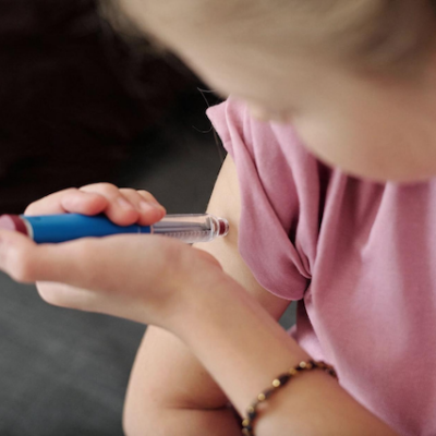 Young girl using an Ozempic pen on herself.