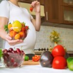 A pregnant woman eats vegetables and fruits.