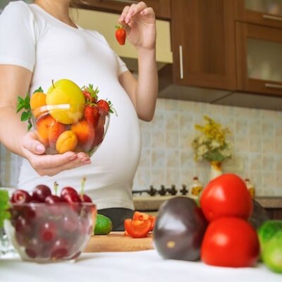 A pregnant woman eats vegetables and fruits.