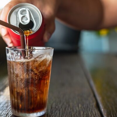 Man pouring diet soda from a can into a glass.