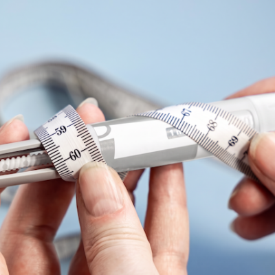 Man holding a Mounjaro pen with a measuring tape.